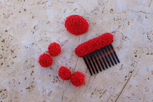 Conjunto de Pendientes largos de metal dorado con dos medias bolas de madroño, Peinecillo y Broche, de color rojo de Colección Mis Buganvillas.