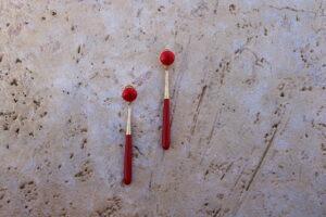Pendientes largos de metal dorado con una estilizada lágrima color rojo de Colección Mis Buganvillas.