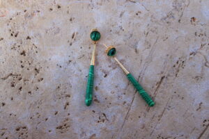 Pendientes largos de metal dorado con una estilizada lágrima color verde de Colección Mis Buganvillas.