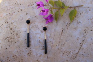 Pendientes largos de metal dorado con una estilizada lágrima color negro de Colección Mis Buganvillas.