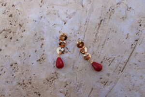 Pendientes largos de metal dorado con 3 arandelas y una lágrima color grosella de Colección Mis Buganvillas.