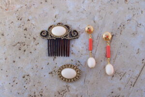 Conjunto de Pendientes largos de metal dorado con cuentas color marfil y coral, peinecillo y broche de Colección Mis Buganvillas.