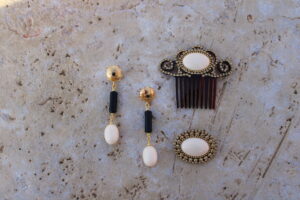 Conjunto de Pendientes largos de metal dorado con cuentas color marfil y negro, peinecillo y broche de Colección Mis Buganvillas.